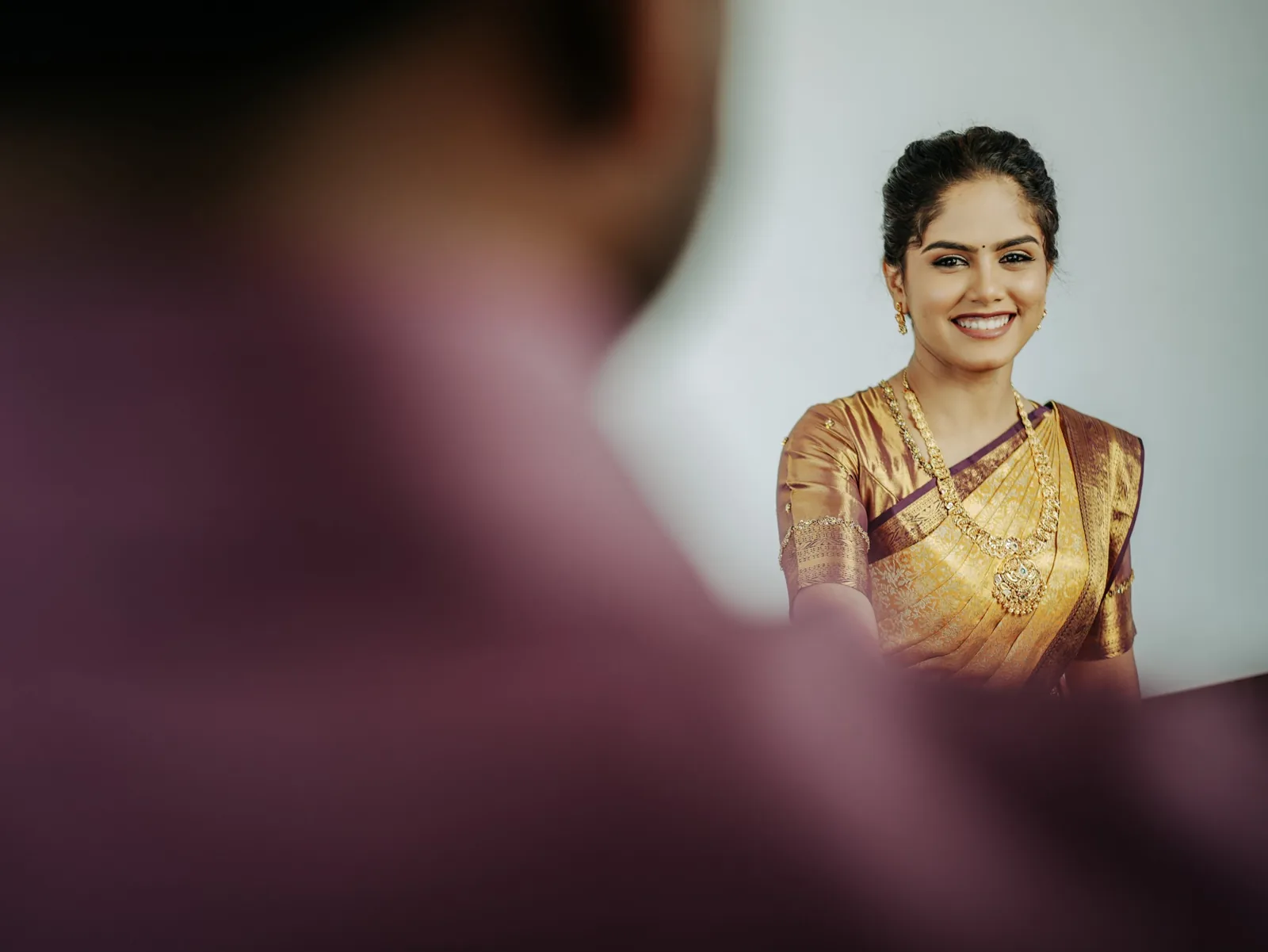 The bride smiling, seen past his shoulder